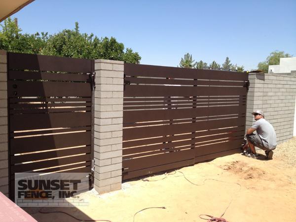 A man is working on the fence of his driveway.