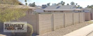 A concrete fence with a house in the background.