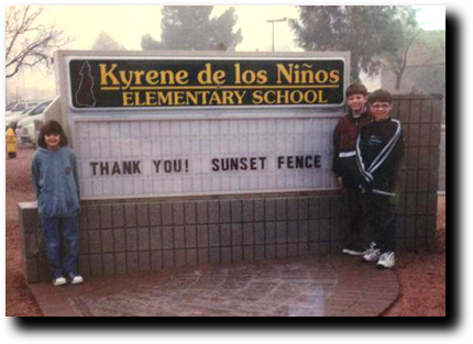 A group of people standing in front of a school sign.